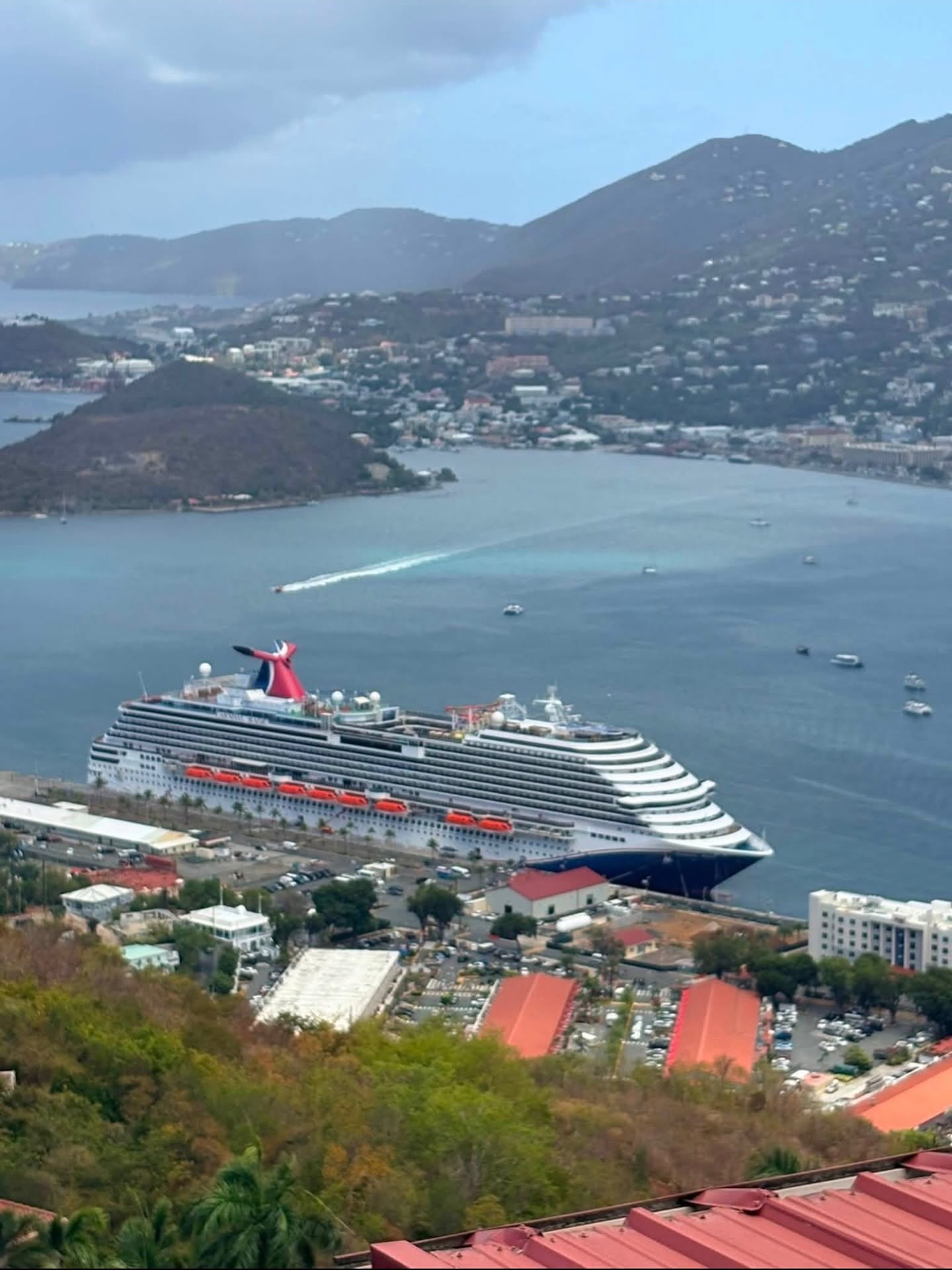 Carnival cruise ship docked in a Caribbean harbor surrounded by green hills